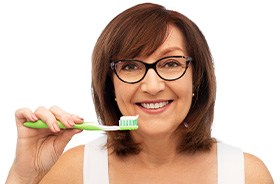 Woman holding toothbrush, caring for oral hygiene after dental implant surgery