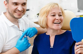 Dental patient looking in mirror, admiring her new teeth
