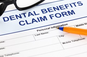 Dental benefits claim form with pen and glasses