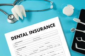 Dental insurance document next to tooth model and stethoscope