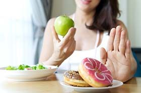 Woman choosing apple over donuts to prevent dental emergencies in Lebanon 