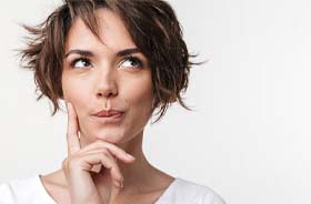 Woman in white shirt, thinking about questions related to dental emergencies