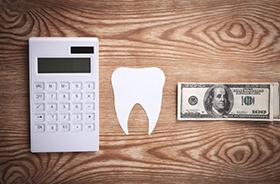 Calculator, tooth cutout, and money on table