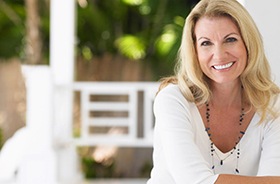 Smiling woman enjoying the money-saving benefits of dental implant