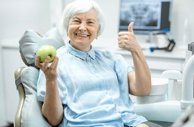 Senior woman giving thumbs up for her implant dentures