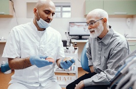 Dentist and senior man discussing candidacy for implant dentures