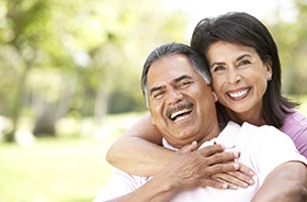 Couple with dental implants in Lebanon laughing outside