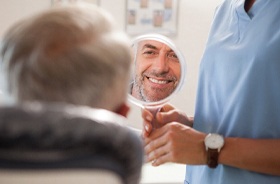 male dental patient looking in mirror admiring repaired teeth
