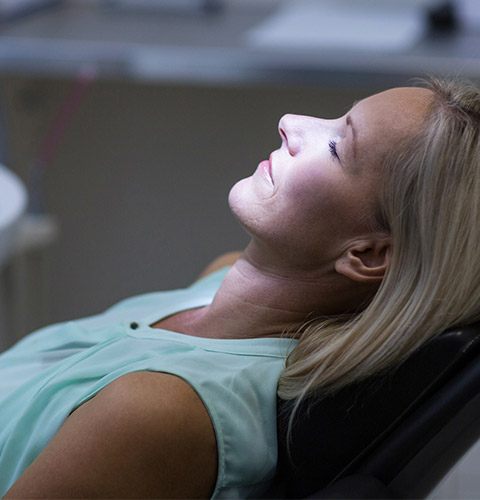 Woman lying back with eyes closed in dental chair