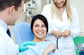 Smiling patient discussing tooth-colored fillings with friendly dentist
