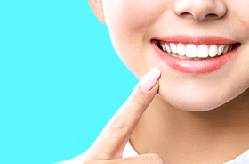 Woman pointing at her smile following teeth whitening in Lebanon