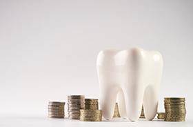 Tooth model next to stacks of coins