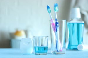 Dental hygiene tools: floss, mouthwash, and two toothbrushes