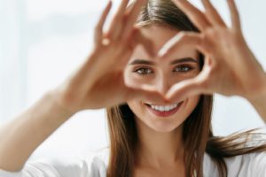 woman with healthy smile making heart shape with hands