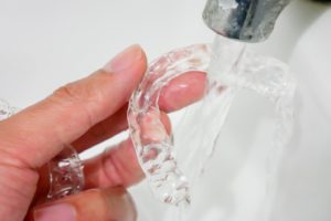 Cleaning Invisalign in Lebanon, rinsing aligner under with water