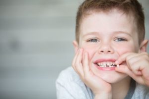 Smiling boy holding his extracted tooth