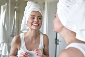 Woman flossing her teeth in front of mirror