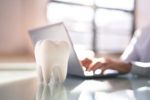 Tooth model in foreground, laptop in background