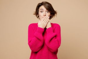 Woman covering her mouth, wearing surprised expression