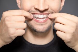 Man placing whitening strip on his teeth