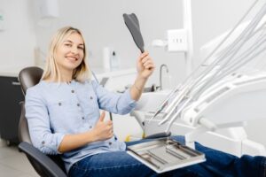 Dental patient holding mirror and making thumbs-up gesture 