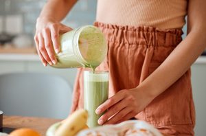 Woman pouring a green smoothie for herself 